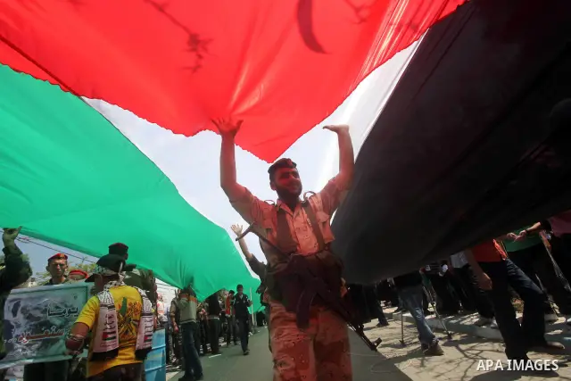 Palestinian Hamas security walk under a large Palestinian flag during a rally marking Al-Nakba, commemorating the displacement of Palestinians in 1948 due to the declaration of the state of Israel, in Gaza City, Gaza Str...