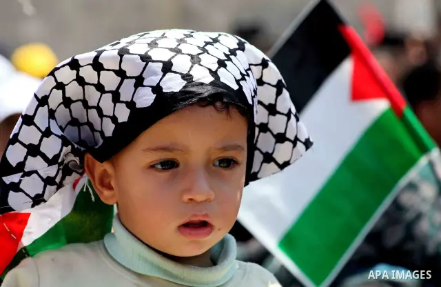 A Palestinian boy wears a scarf with the colours of the Palestinian flag during a rally in Gaza City on May 15, 2012 to mark Nakba day, which commemorates the exodus of hundreds of thousands of their kin after the establ...