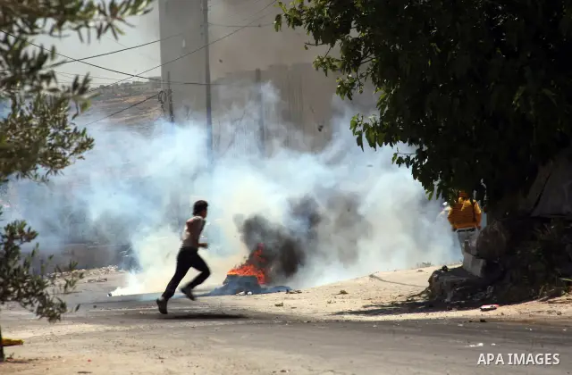 Palestinian boys throw stones towards Israeli soldiers deployed at the entrance of the al-Aroub Palestinian refugee camp, just north the West Bank town of Hebron on May 15, 2012, as Palestinians mark Nakba day, which com...