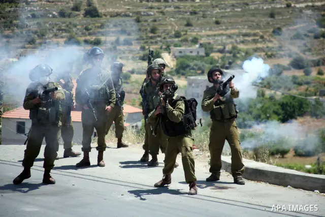 Israeli soldiers fire teargas, towards Palestinian stone throwers deployed at the entrance of the al-Aroub Palestinian refugee camp, just north the West Bank town of Hebron on May 15, 2012, as Palestinians mark Nakba day...