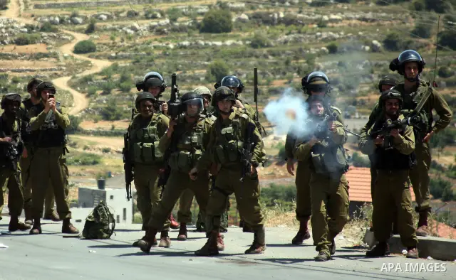 Israeli soldiers fire teargas, towards Palestinian stone throwers deployed at the entrance of the al-Aroub Palestinian refugee camp, just north the West Bank town of Hebron on May 15, 2012, as Palestinians mark Nakba day...