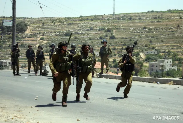Israeli soldiers fire teargas, towards Palestinian stone throwers deployed at the entrance of the al-Aroub Palestinian refugee camp, just north the West Bank town of Hebron on May 15, 2012, as Palestinians mark Nakba day...
