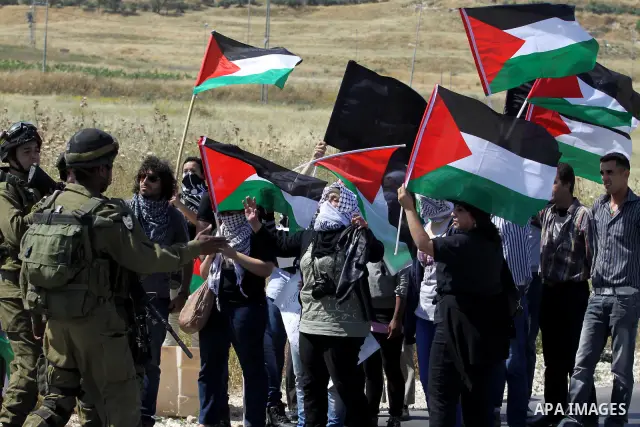 Israeli soldiers stand face to Palestinian and foreign activists who hold Palestinian flags during a demonstration marking the 64th anniversary of the 'Nakba' ('catastrophe'), at the Hawara checkpoint near the West Bank...