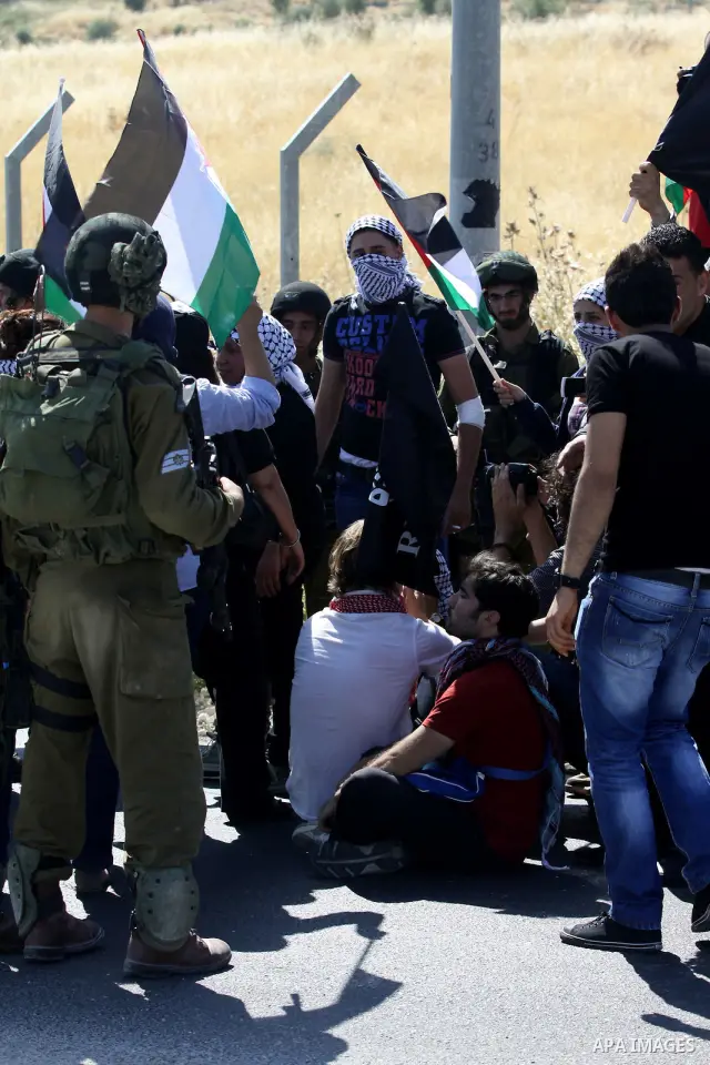 Israeli soldiers stand face to Palestinian and foreign activists who hold Palestinian flags during a demonstration marking the 64th anniversary of the 'Nakba' ('catastrophe'), at the Hawara checkpoint near the West Bank...