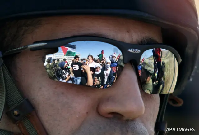 Israeli soldiers stand face to Palestinian and foreign activists who hold Palestinian flags during a demonstration marking the 64th anniversary of the 'Nakba' ('catastrophe'), at the Hawara checkpoint near the West Bank...