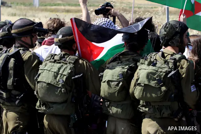 Israeli soldiers stand face to Palestinian and foreign activists who hold Palestinian flags during a demonstration marking the 64th anniversary of the 'Nakba' ('catastrophe'), at the Hawara checkpoint near the West Bank...