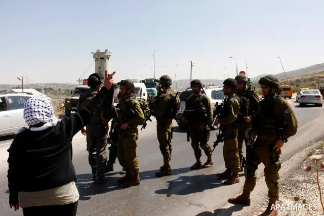 Israeli soldiers stand face to Palestinian and foreign activists who hold Palestinian flags during a demonstration marking the 64th anniversary of the 'Nakba' ('catastrophe'), at the Hawara checkpoint near the West Bank...