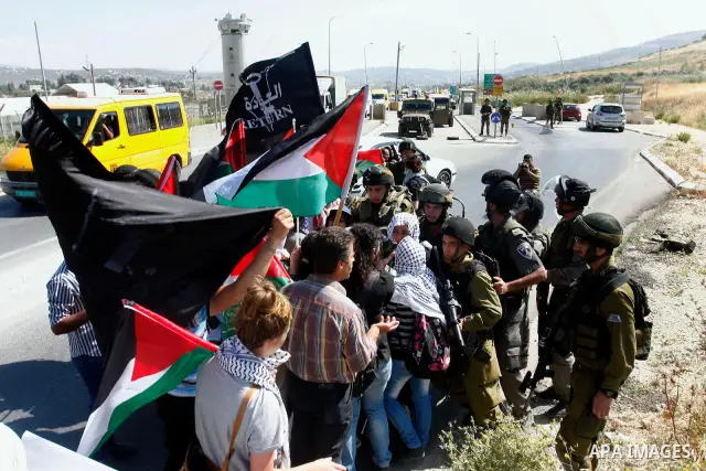 Israeli soldiers stand face to Palestinian and foreign activists who hold Palestinian flags during a demonstration marking the 64th anniversary of the 'Nakba' ('catastrophe'), at the Hawara checkpoint near the West Bank...