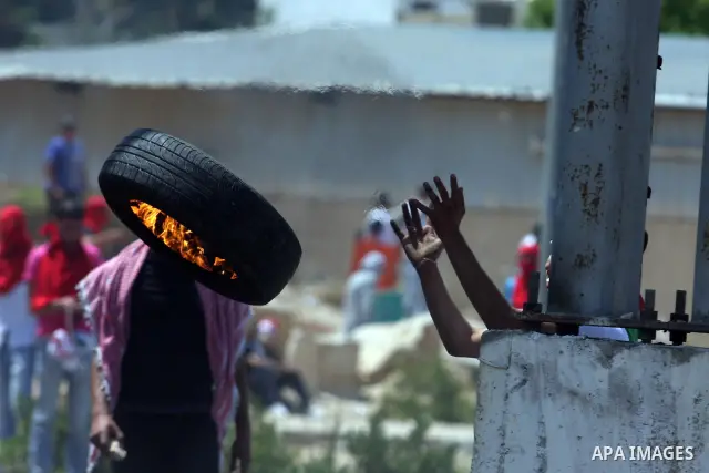 A Palestinian protester burns a tire, during clashes on Nakba Day near Ofer prison, near Ramallah, the West Bank, 15 May 2012. Thousands marched in the West Bank and Gaza Strip, commemorating the dispersal of hundreds of...