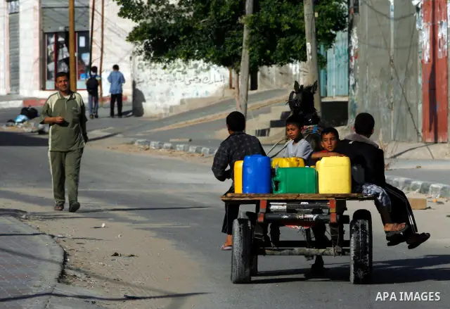 Palestinian children filling plastic bottles and jerry cans with drinking water from a public tap in the southern Gaza Strip refugee camp of Rafah on May 16, 2012. Photo by Eyad Al Baba