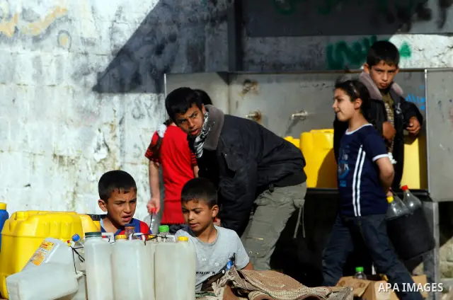 Palestinian children filling plastic bottles and jerry cans with drinking water from a public tap in the southern Gaza Strip refugee camp of Rafah on May 16, 2012. Photo by Eyad Al Baba