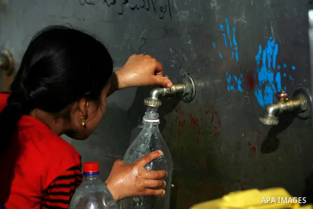 Palestinian children filling plastic bottles and jerry cans with drinking water from a public tap in the southern Gaza Strip refugee camp of Rafah on May 16, 2012. Photo by Eyad Al Baba