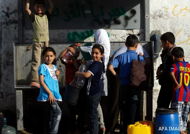 Palestinian children filling plastic bottles and jerry cans with drinking water from a public tap in the southern Gaza Strip refugee camp of Rafah on May 16, 2012. Photo by Eyad Al Baba