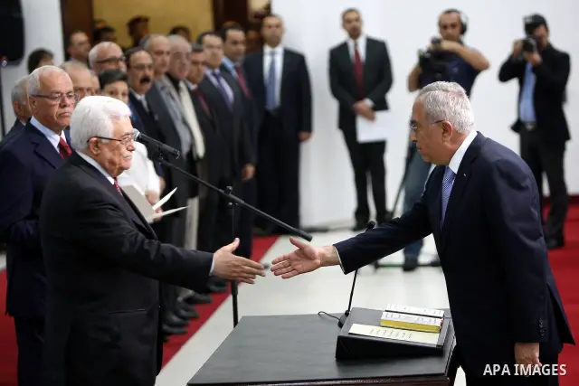Palestinian National Authority President Mahmoud Abbas and his Prime Minister Salam Fayyad, receive the new government Ministers during the swearing in ceremony of the new cabinet, at Abbas's headquarters in the West Ban...