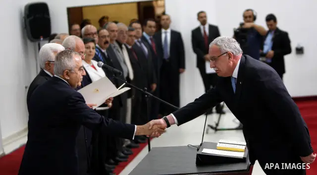 Palestinian National Authority President Mahmoud Abbas and his Prime Minister Salam Fayyad, receive the new government Ministers during the swearing in ceremony of the new cabinet, at Abbas's headquarters in the West Ban...