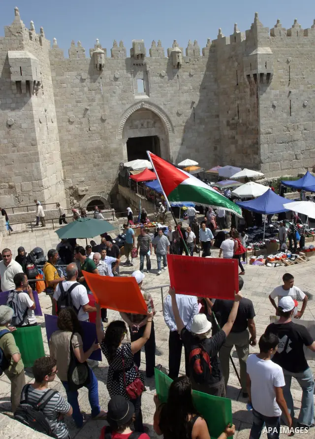 Palestinian and foreign activists hold Palestinian flags and slogans outside Damascus gate in Jerusalem's Old City, during a protest against land confiscation in the neighborhood of Sheikh Jarrah in the east Jerusalem on...