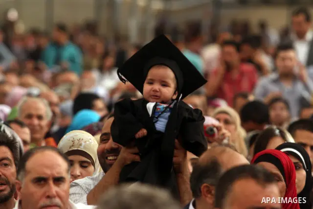 A Palestinian child wears a costume graduation, during the graduation ceremony at the Birzeit University near the West Bank city of Ramallah. as some 3000 students received their degrees at the end of the academic year o...