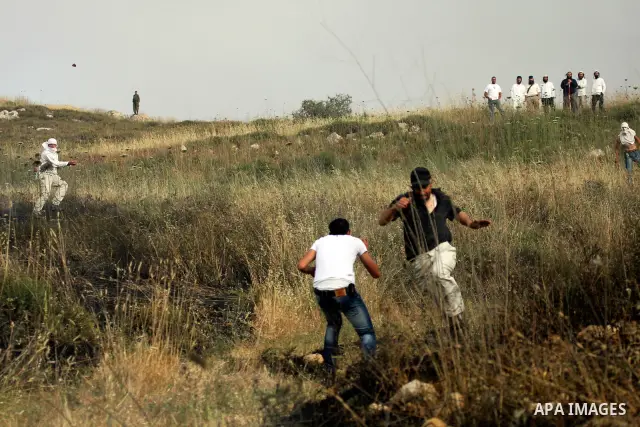 Israeli settlers from the Jewish settlement of Yitzhar throw stones during clashes with Palestinians from the village of Asira al-Qibiliya, south of the northern West Bank city of Nablus on May 19, 2012. The Israeli army...
