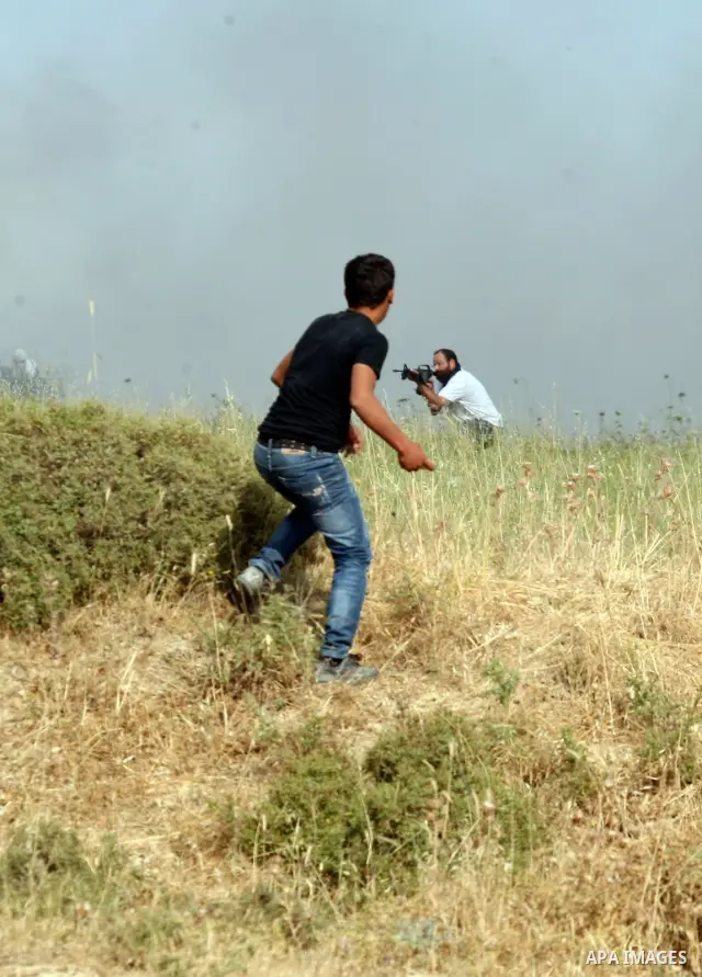 A Palestinians man from the village of Asira al-Qibiliya throws stones during clashes with Israeli settlers from the Jewish settlement of Yitzhar, south of the northern West Bank city of Nablus on May 19, 2012. The Israe...
