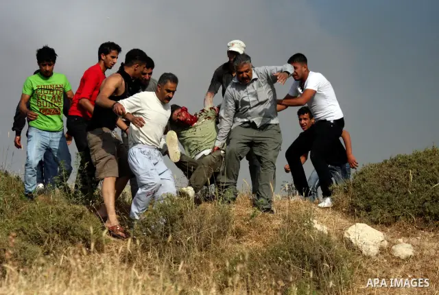 Palestinians carry an injured man, during clashes between Israeli settler from the Jewish settlement of Yitzhar and Palestinians from the village of Asira al-Qibiliya, south of the northern West Bank city of Nablus on Ma...