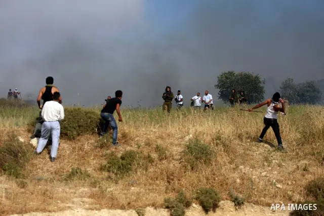 Palestinians from the village of Asira al-Qibiliya throw stones during clashes with Israeli settlers from the Jewish settlement of Yitzhar, south of the northern West Bank city of Nablus on May 19, 2012. The Israeli army...