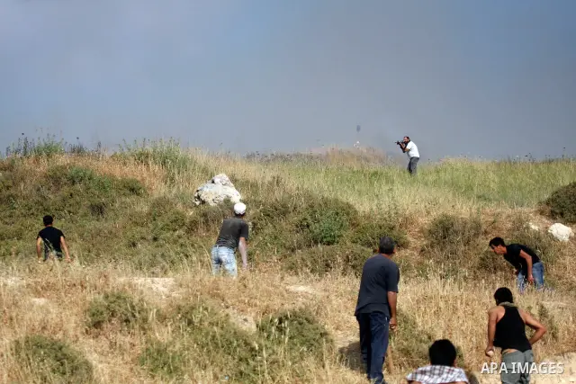 Palestinians from the village of Asira al-Qibiliya throw stones during clashes with Israeli settlers from the Jewish settlement of Yitzhar, south of the northern West Bank city of Nablus on May 19, 2012. The Israeli army...