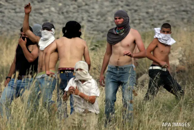 Israeli settlers from the Jewish settlement of Yitzhar throw stones during clashes with Palestinians from the village of Asira al-Qibiliya, south of the northern West Bank city of Nablus on May 19, 2012. The Israeli army...