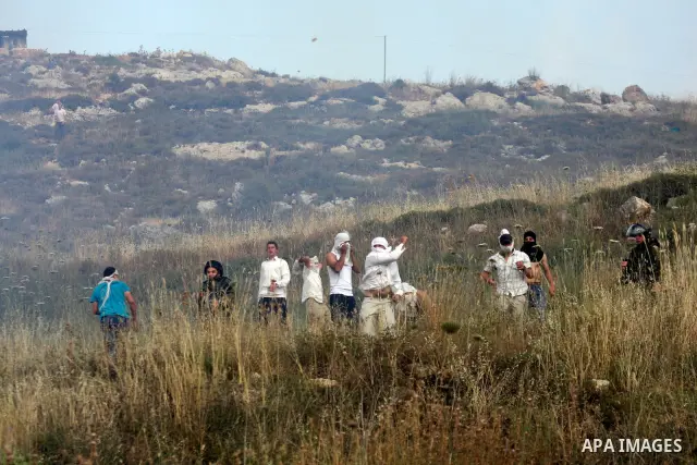 Israeli settlers from the Jewish settlement of Yitzhar throw stones during clashes with Palestinians from the village of Asira al-Qibiliya, south of the northern West Bank city of Nablus on May 19, 2012. The Israeli army...