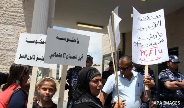 Hundreds of Palestinian workers, hold a banners during a demonstration in front of prime minister Salam Fayyad's offices for the fixing of a minimum wage, and against corruption, prohibitively high prices and the lack of...