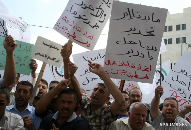 Hundreds of Palestinian workers, hold a banners during a demonstration in front of prime minister Salam Fayyad's offices for the fixing of a minimum wage, and against corruption, prohibitively high prices and the lack of...