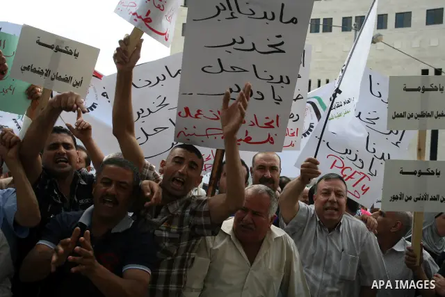 Hundreds of Palestinian workers, hold a banners during a demonstration in front of prime minister Salam Fayyad's offices for the fixing of a minimum wage, and against corruption, prohibitively high prices and the lack of...