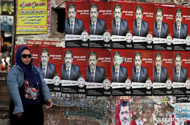 An Egyptian woman walks past election campaign posters for the Muslim Brotherhood's presidential candidate, Mohammed Mursi, in Cairo on May 21, 2012. The Supreme Council of the Armed Forces urged Egyptians to accept the...