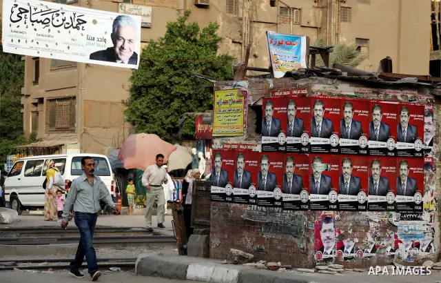 Egyptians walk behind an election campaign banner for the presidential candidate, Hamdin Sabahi, in Cairo on May 21, 2012. The Supreme Council of the Armed Forces urged Egyptians to accept the results of a looming presid...