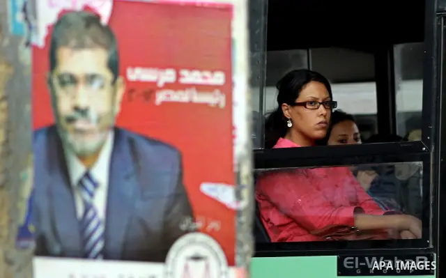 An Egyptian woman in a bus behind election campaign posters for the Muslim Brotherhood's presidential candidate, Mohammed Mursi, in Cairo on May 21, 2012. The Supreme Council of the Armed Forces urged Egyptians to accept...