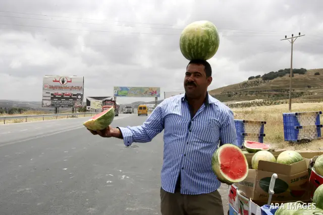 A Palestinian fruit vendors balance watermelons on their head as they try to attract customers in the West Bank town of Nablus near Hawara checkpoint, on May 22, 2012. Photo by Wagdi Eshtayah
