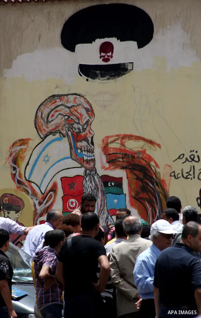 An artist writes a slogan in Arabic that reads "I will never give you peace" next to a graffiti picturing the morphed faces of ousted president Hosni Mubarak (R) and military ruler Hussein Tantawi and presidential candid...