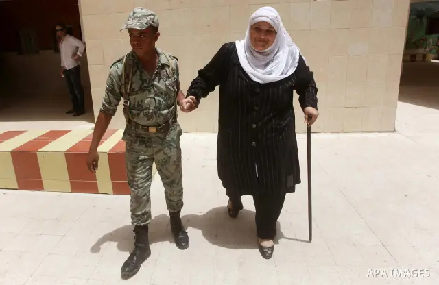 Egyptian security man helps a woman to casting her ballot in the first round of Egypt's presidential elections, at a polling station in Cairo, Egypt, 23 May 2012. Egyptian voters, on 23 May, queued at polling stations fo...