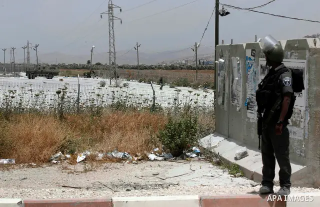 An Israeli soldier looks at a blindfolded and handcuffed Palestinian youth, as he sits in the back of a car after he was arrested at the Hawara checkpoint on the southern edge of the northern Palestinian city of Nablus i...