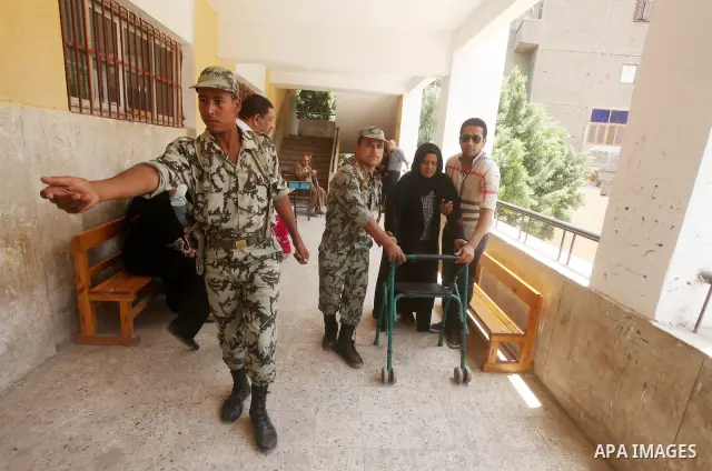 Egyptian policemen help a old woman to vote during second day of the first round of Egypt's presidential elections in Cairo, Egypt, 24 May 2012. Media reports quoting state-television and observers said that far less Egy...