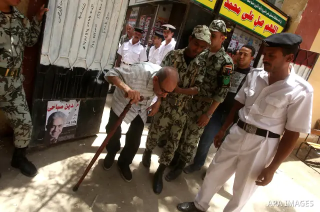 Egyptian policemen help a old man to vote during second day of the first round of Egypt's presidential elections in Cairo, Egypt, 24 May 2012. Media reports quoting state-television and observers said that far less Egypt...
