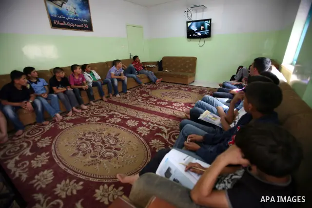 Palestinian orphan children watch TV at the Hebron's orphan house, in the West Bank city of Hebron 24 May 2012. Hebron's orphan house contain about 100 orphan children from ages 6 to 18 years old, and oversees some of or...