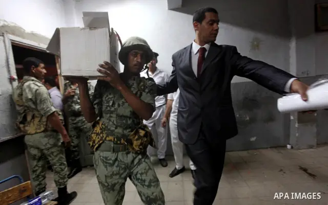 An Egyptian policeman takee sealed ballet box for the election officials to count ballots of the first round of Egypt's presidential elections, in a polling station in Cairo, Egypt, at the end of the election's second da...