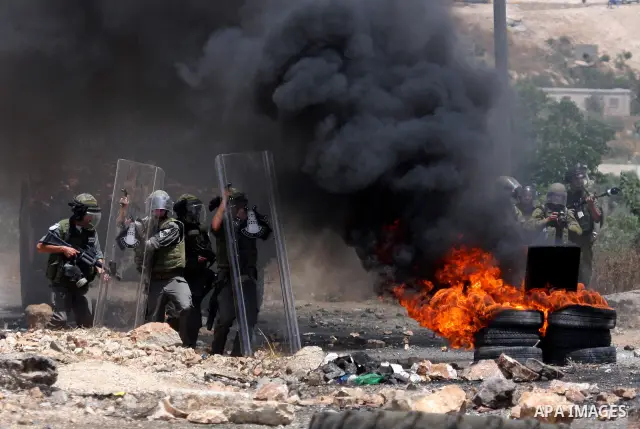 Israeli soldiers wearing gas masks walk through black smoke rising from burning tyres during clashes in the northern West Bank village of Kufr Qaddum, near the Jewish settlement of Kdumim, on May 25, 2012. Photo by Wagdi...