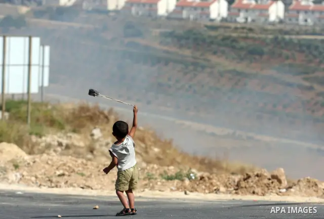A Palestinian child holds a sling shot during clashes between stone throwers and Israeli soldiers in the West Bank village of Nabi Saleh, near Ramallah, on May 25, 2012 following a protest against the confiscation of Pal...