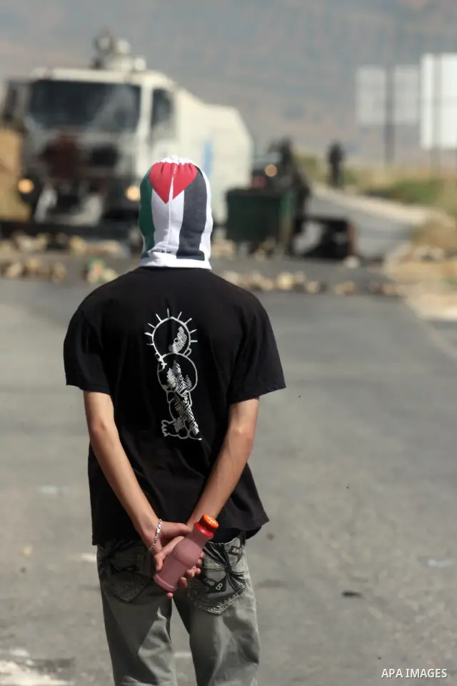 A masked Palestinian protester hurls stones during clashes between stone throwers and Israeli soldiers in the West Bank village of Nabi Saleh, near Ramallah, on May 25, 2012 following a protest against the confiscation o...