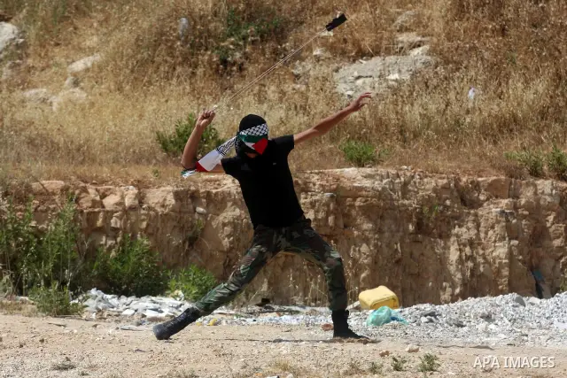 A masked Palestinian protester hurls stones during clashes between stone throwers and Israeli soldiers in the West Bank village of Nabi Saleh, near Ramallah, on May 25, 2012 following a protest against the confiscation o...