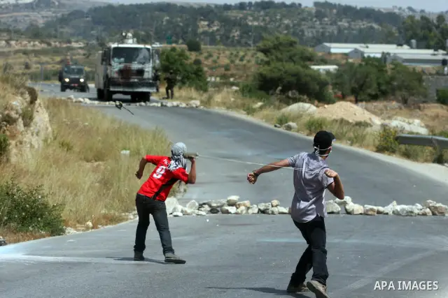 A masked Palestinian protester hurls stones during clashes between stone throwers and Israeli soldiers in the West Bank village of Nabi Saleh, near Ramallah, on May 25, 2012 following a protest against the confiscation o...