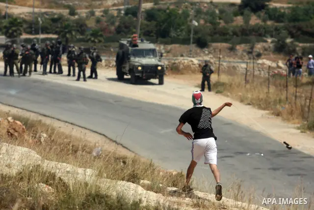A masked Palestinian protester hurls stones during clashes between stone throwers and Israeli soldiers in the West Bank village of Nabi Saleh, near Ramallah, on May 25, 2012 following a protest against the confiscation o...