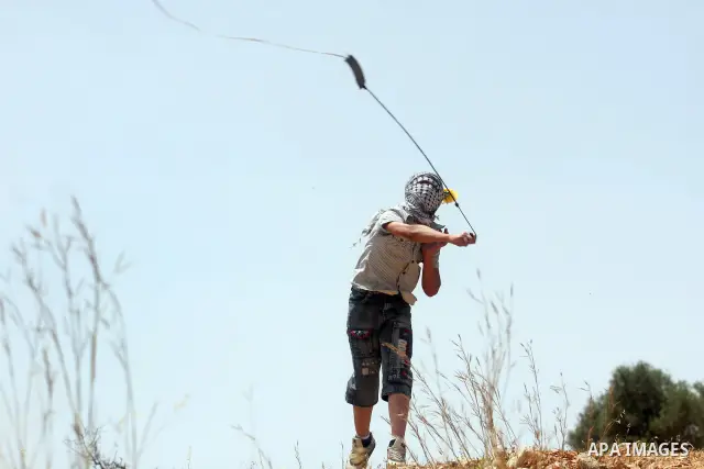 A masked Palestinian protester hurls stones during clashes between stone throwers and Israeli soldiers in the West Bank village of Nabi Saleh, near Ramallah, on May 25, 2012 following a protest against the confiscation o...