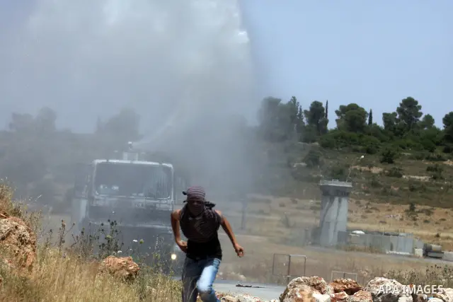 Israeli truck spray foul smelling water towards Palestinian protesters during clashes between stone throwers and Israeli soldiers in the West Bank village of Nabi Saleh, near Ramallah, on May 25, 2012 following a protest...